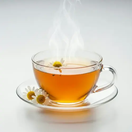 a glass cup of chamomile tea with steam rising, garnished with chamomile flowers on the saucer