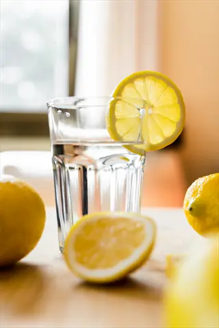 a glass of water with lemon slice and surrounding lemons on a table, illustrating beverage modifications