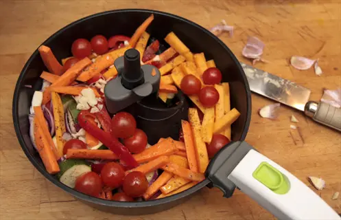 air fryer vegetables prep: colorful mix of carrots, cherry tomatoes, bell peppers, zucchini, and garlic in a pan on a wooden board