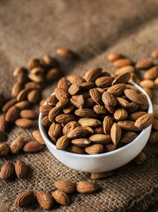 almonds closeup in a white bowl on burlap (rich in vitamin e)