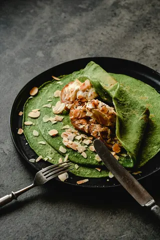almonds spinach crepes with magnesium-rich ingredients on dark plate, served with cutlery