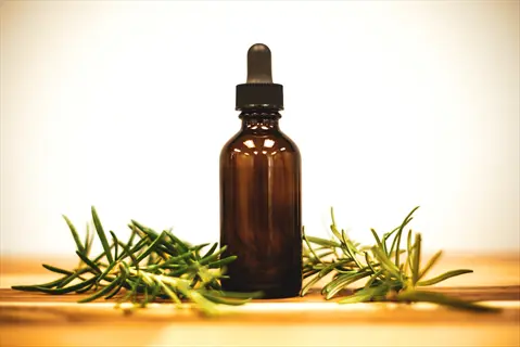 amber glass dropper bottle with fresh rosemary sprigs on a wooden surface, representing healthy oils bottles for natural fat source selection