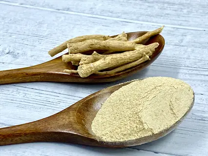 ashwagandha roots and powder in wooden spoons on weathered wood background