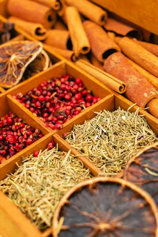 assorted dried herbs spices collection in compartmentalized boxes with cinnamon sticks, red peppercorns, and dried citrus slices as salt alternatives