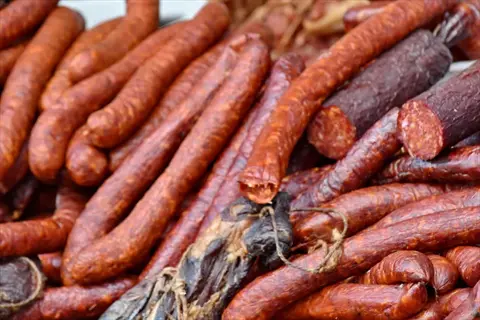 assortment of sausage ingredients featuring various cured and dried meat products piled together, with some tied in bundles