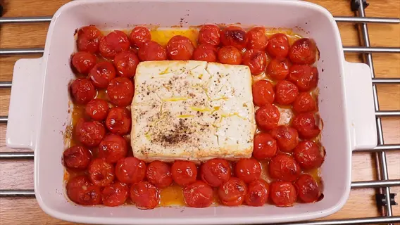 baked feta and cherry tomatoes in a white baking dish with olive oil and herbs, on a wire rack