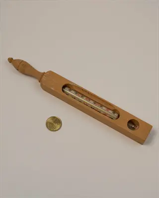 bath thermometer: antique wooden bath thermometer with mercury tube and temperature scale, shown with coin for size comparison