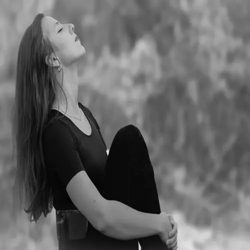 black and white photo of a woman meditating calmly in nature, eyes closed and head tilted back