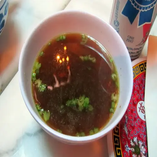 bone broth bowl with scallions, a 'one pint' beer can, and an ornate decorative plate