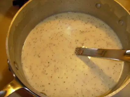 bone broth gravy in a pot with spoon, creamy sauce with specks