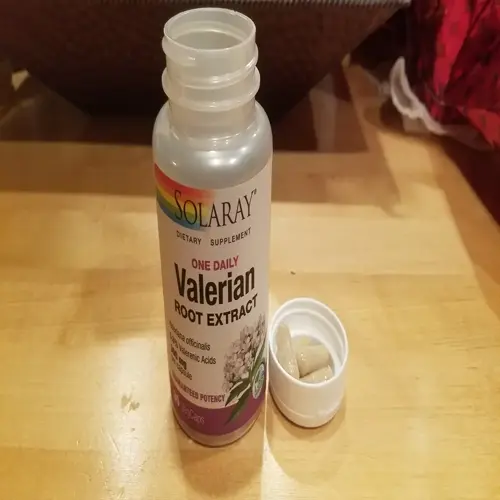 bottle of solaray valerian root extract capsules with open cap and capsules beside it