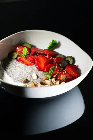 bowl of chia seed pudding topped with fresh strawberries, blueberries, kiwi slices, almonds, and mint, using chia seeds as a salad topping
