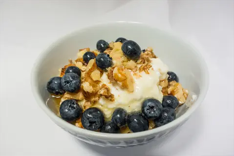 bowl of greek yogurt topped with fresh blueberries and walnuts - embodies 'greek yogurt berries' and 'greek yogurt'