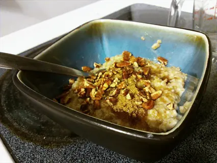 bowl of steel cut oats with pecans and cinnamon on a stovetop
