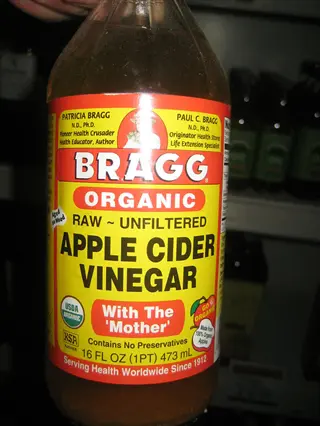 bragg organic apple cider vinegar bottle labeled 'raw ~ unfiltered' with 'with the mother', showing certifications and liquid inside