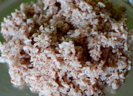 brown rice cooked: close-up of steamed brown rice grains with light brown hue and fluffy texture on a green plate