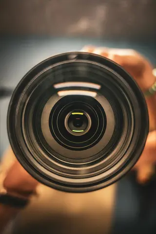 camera perspective focus: close-up of a dslr camera lens with shallow depth of field, held by hands, embodying photography through technical precision