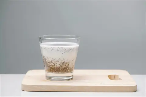 chia seeds soaked in milk, served in a glass on a wooden cutting board