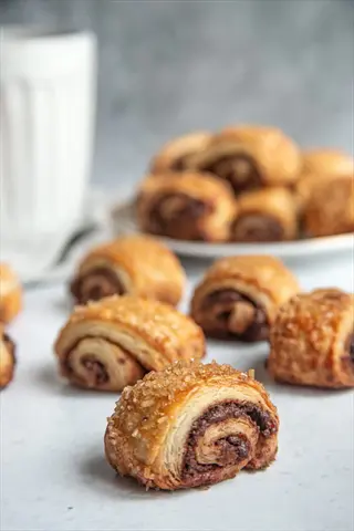 cinnamon oil baking: freshly baked cinnamon swirl pastries with a plate of more in the background; culinary flavor enhancer in pastry form