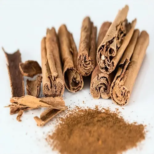 cinnamon sticks and powder: close-up of rolled cinnamon bark and ground spice on white background
