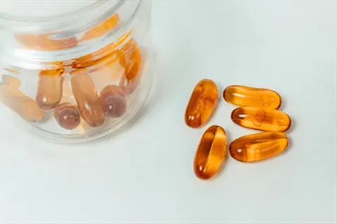 clear bottle containing vitamin capsules with additional loose capsules on white background, representing supplement guidance