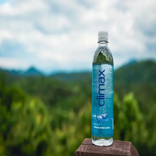 climax premium spring mineral water bottle in nature setting on wooden post with mountain and green forest background
