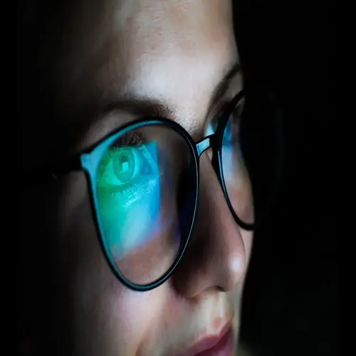 close-up of a person wearing blue blocking glasses with light reflection on the lenses