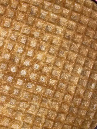 close-up of a waffle grid texture resembling ice cream toppings or bases, with golden-brown hues and repetitive square patterns