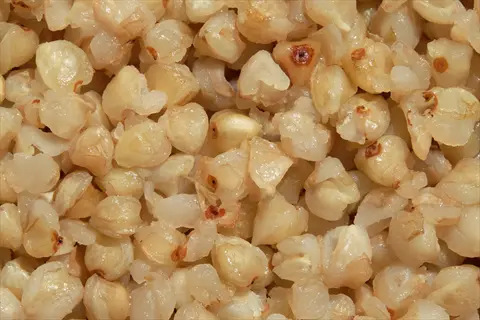 close-up of buckwheat groats: light tan, triangular seeds with some showing dark centers, densely packed together