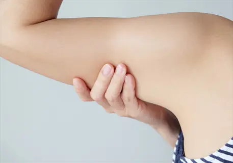 close-up of human arm skin with hand touching the upper arm, showing smooth skin texture and shoulder area
