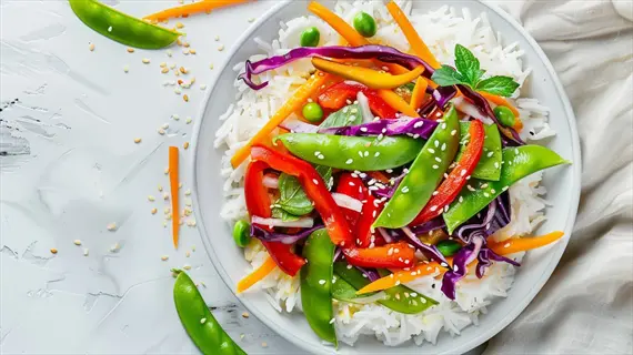 colorful vegetable plate with rice base, snap peas, bell peppers, purple cabbage, carrots and sesame seeds - nutrient awareness