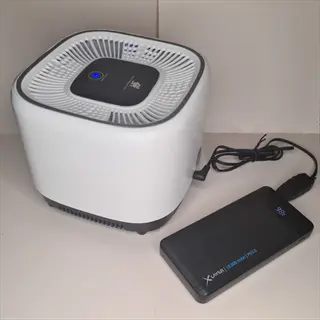 compact hepa air purifier home device with blue indicator light, connected to an xlayer power bank via usb cable