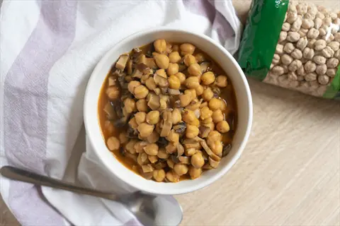 cooked chickpeas bowl with mushrooms in broth, packaged dry chickpeas and spoon on striped cloth