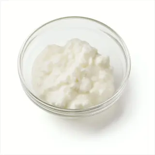cottage cheese in a clear glass bowl on white background