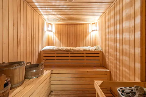 cozy steam room interior with wooden benches, traditional sauna buckets, and warm ambient lighting