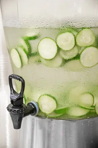 cucumber-infused water in a glass beverage dispenser with metal spigot, showcasing vegetable hydration impact