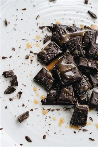dark chocolate pieces with caramel drizzle on white plate - includes 'dark chocolate pieces' and embodies 'dark chocolate'