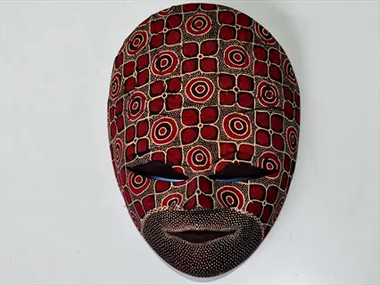 decorated art masks: handcrafted wooden mask with intricate red concentric circles, black geometric patterns, and beige dotted textures, embodying mask making traditions
