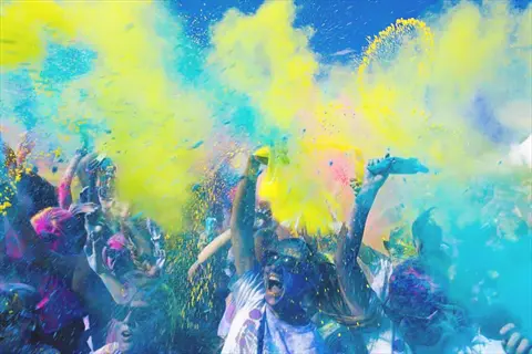diverse art group celebrating with vibrant color powder in the air, symbolizing cultural sensitivity and joyful artistic expression