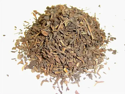 dried valerian root tea fragments: brown, fragmented roots piled on white background
