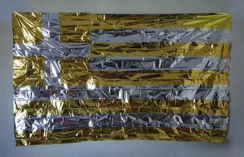 emergency thermal blanket with gold and silver metallic stripes hung on wall