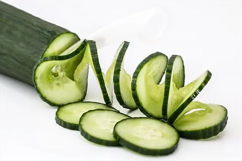 fresh cucumber slices: whole cucumber, spiral-cut segments, and flat rounds arranged on white background with visible seeds and green rind
