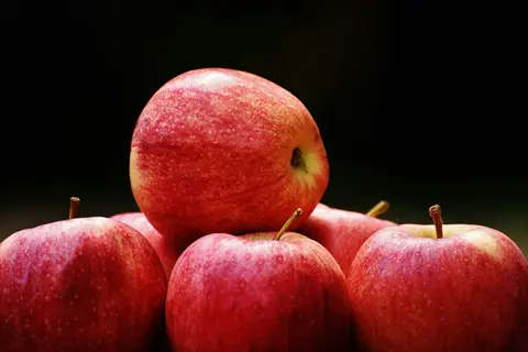 fresh red apples with glossy skin and dewdrop-like speckles, stacked against dark background