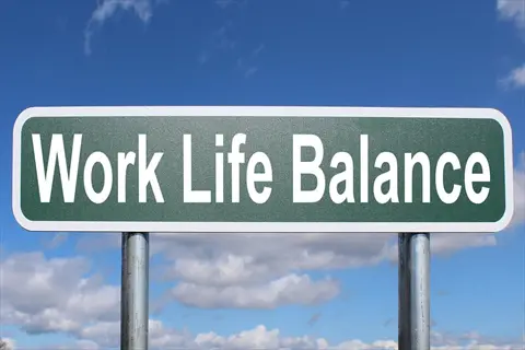 green street sign displaying 'work life balance' against a blue sky with clouds