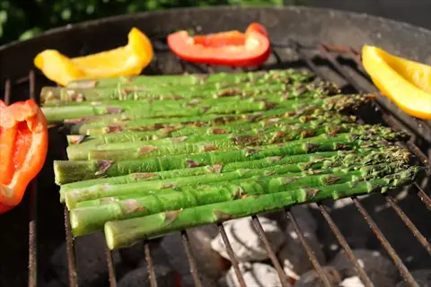 grilled asparagus spears with bell pepper slices on a barbecue grill
