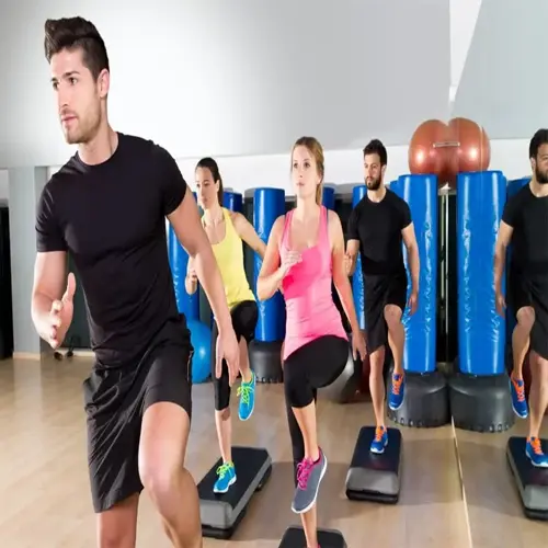 group performing step aerobics as low impact cardio exercise in fitness studio with punching bags and stability balls