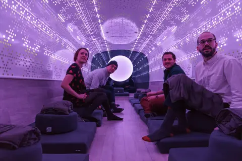 group practicing bus meditation in a futuristic illuminated relaxation pod with cushioned seating and ambient lighting, embodying serene commute contemplation