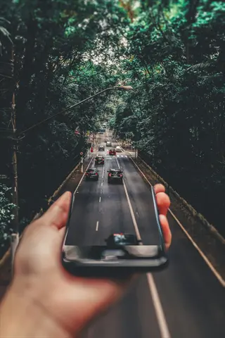 hand holding phone with nature-surrounded road as lock screen wallpaper - digital boundaries concept