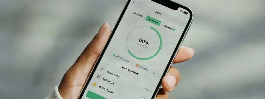 hand holding smartphone displaying hydration tracking app interface with 60% progress circle and recently added beverages (water, tea, glow) for monitoring tools for hydration