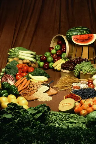 healthy food variety: abundant fresh fruits, vegetables, nuts, and grains artfully arranged in baskets on a brown backdrop